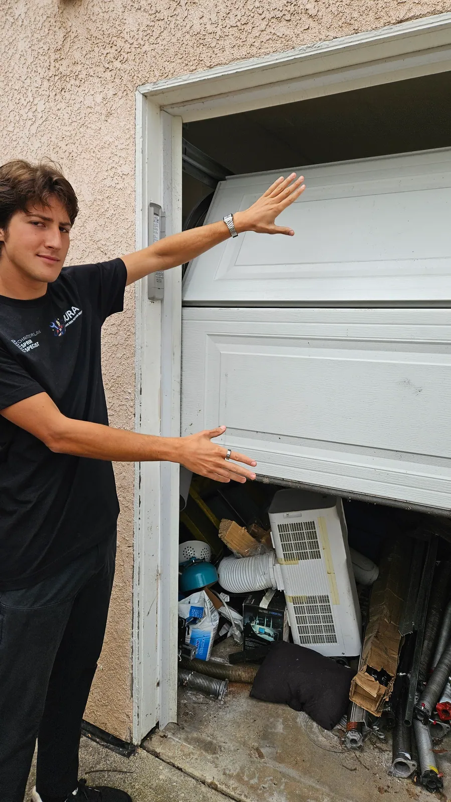 Aura technician holding up a garage door section that has dropped out of its track