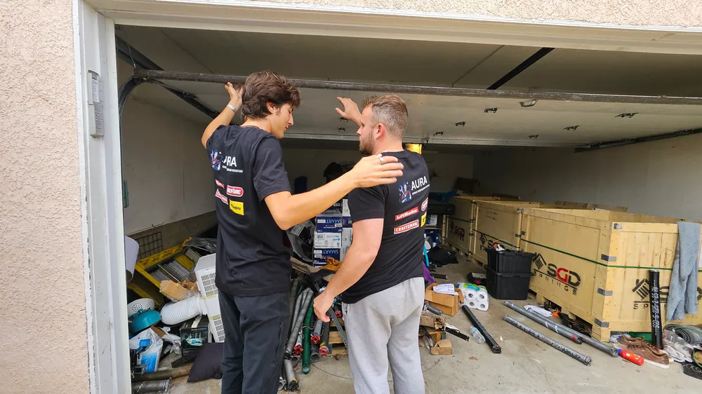 Two Aura technicians talking through a garage door repair inside the garage