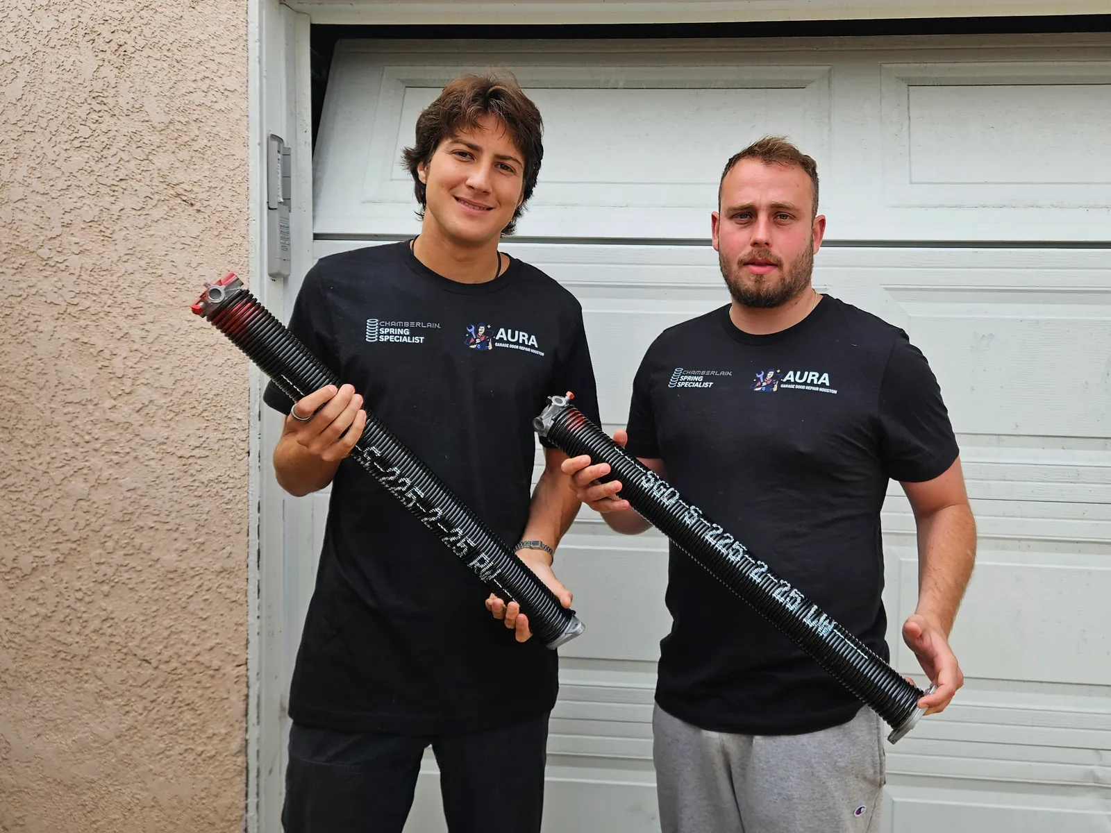 Two Aura technicians holding torsion springs