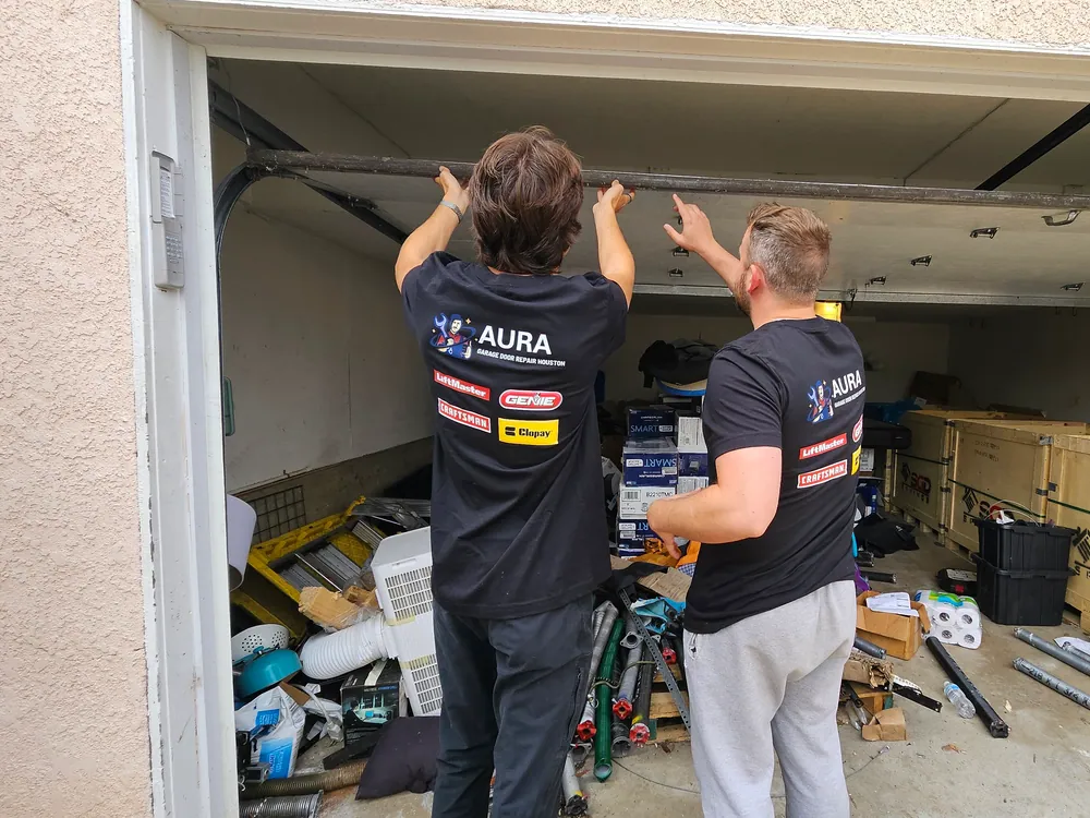 Two Aura technicians checking the torsion bar above an open garage door