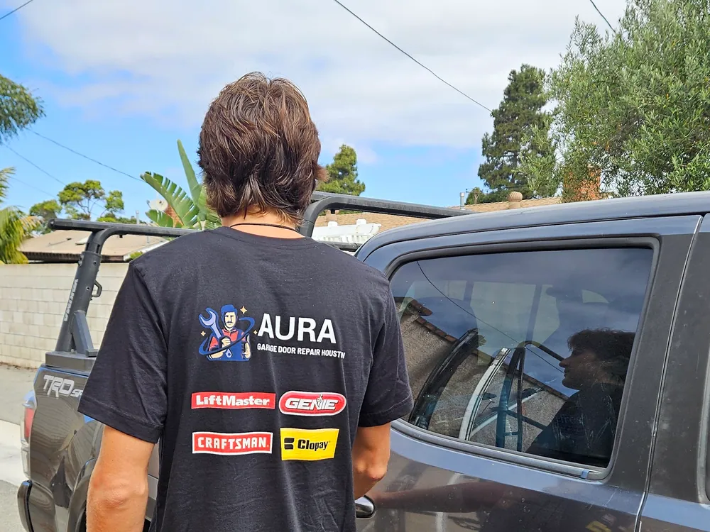 Aura technician in a branded shirt beside a pickup truck