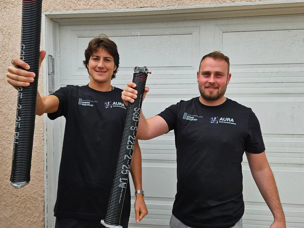 Two Aura technicians holding replacement torsion springs
