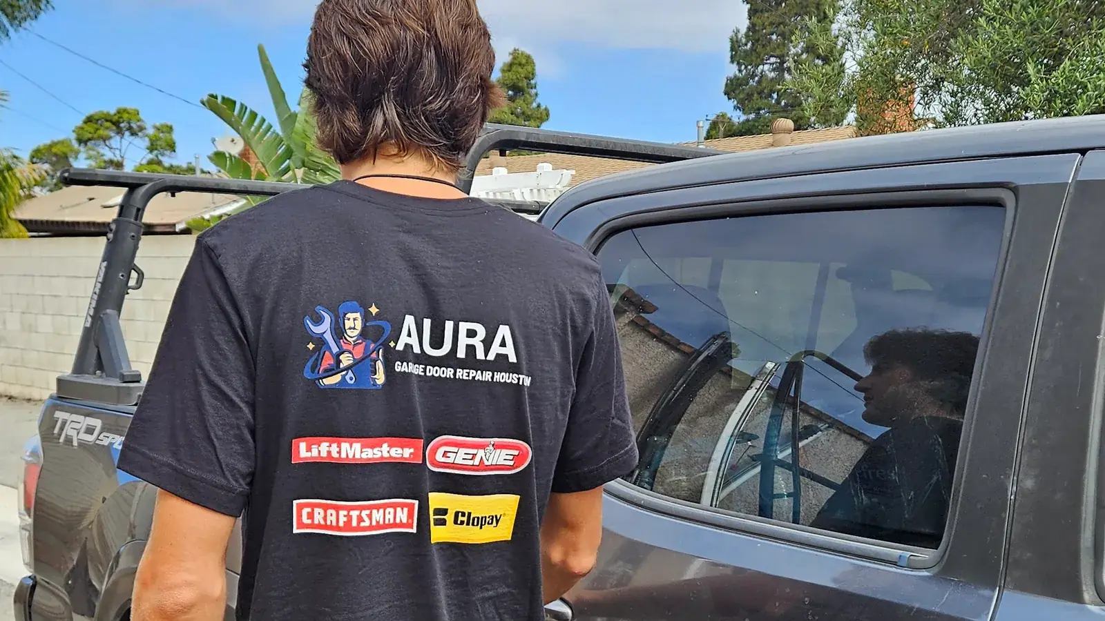 Aura technician beside a pickup truck on a residential street